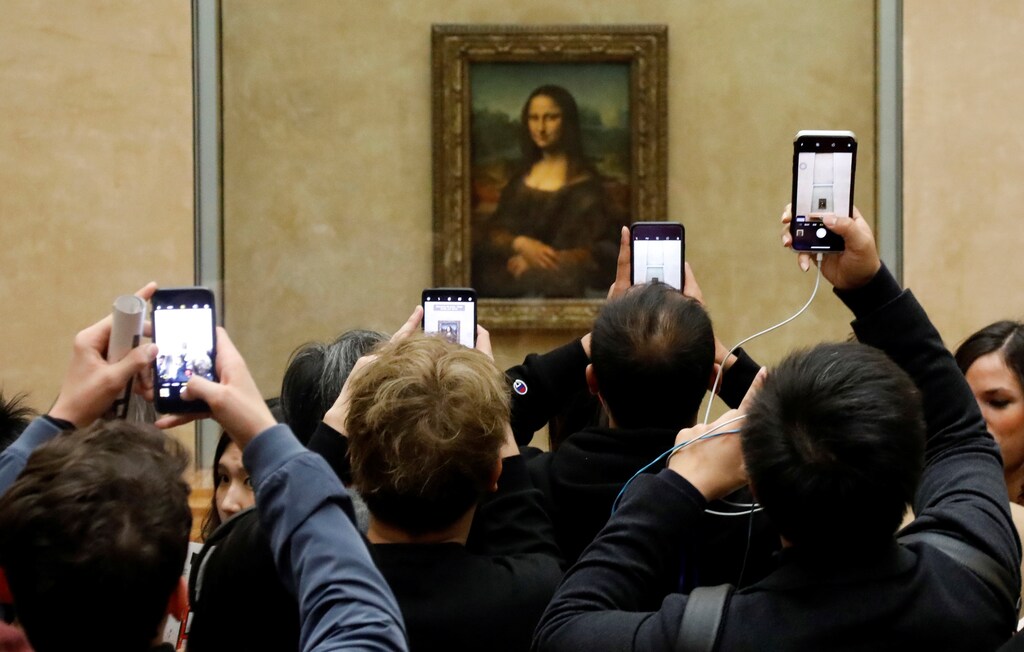 Visitors take pictures of the Mona Lisa by Leonardo da Vinci at the Louvre museum in Paris.