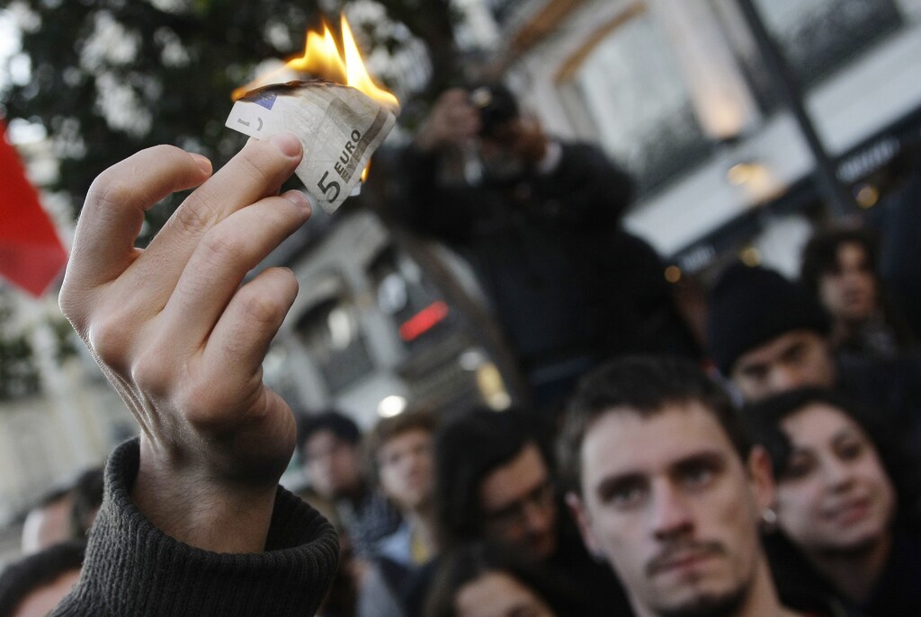 A demonstrator burns a five euro note during a protest in downtown Madrid against capitalism and the G20 Summit on Financial Markets and the World Economy November 15, 2008. REUTERS/Susana Vera (SPAIN) - GM1E4BG08H201