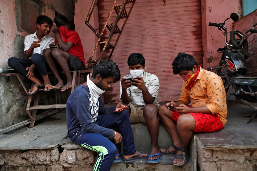 A group of boys look at their mobile phones, during a nationwide lockdown in India to slow the spread COVID-19, in Dharavi, one of Asia's largest slums, during the coronavirus disease outbreak, in Mumbai, India, April 9, 2020. REUTERS/Francis Mascarenhas SEARCH "CORONAVIRUS MUMBAI SLUM" FOR THIS STORY. SEARCH "WIDER IMAGE" FOR ALL STORIES. - RC2Z7G9QKZ3D