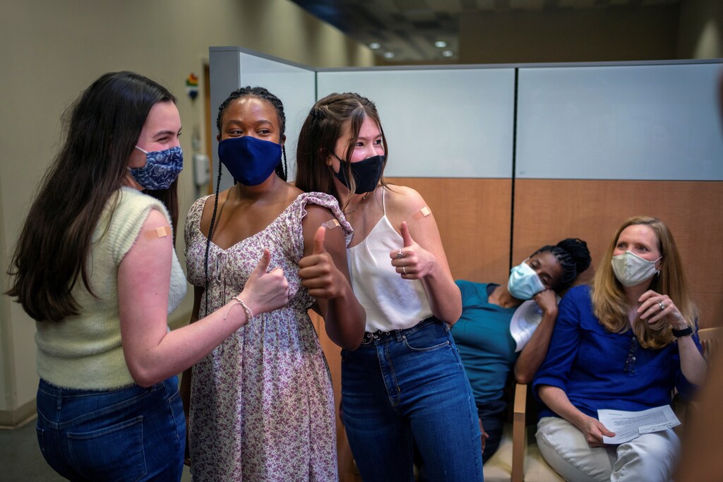 teenagers give a thumbs up after receiving their first dose of the COVID-19 vaccine