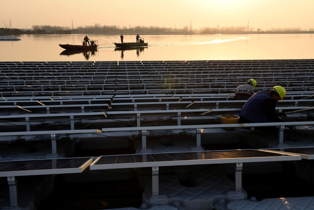 Workers install floating solar panels at a plant in China's Three Gorges Group, in Huainan, Anhui province