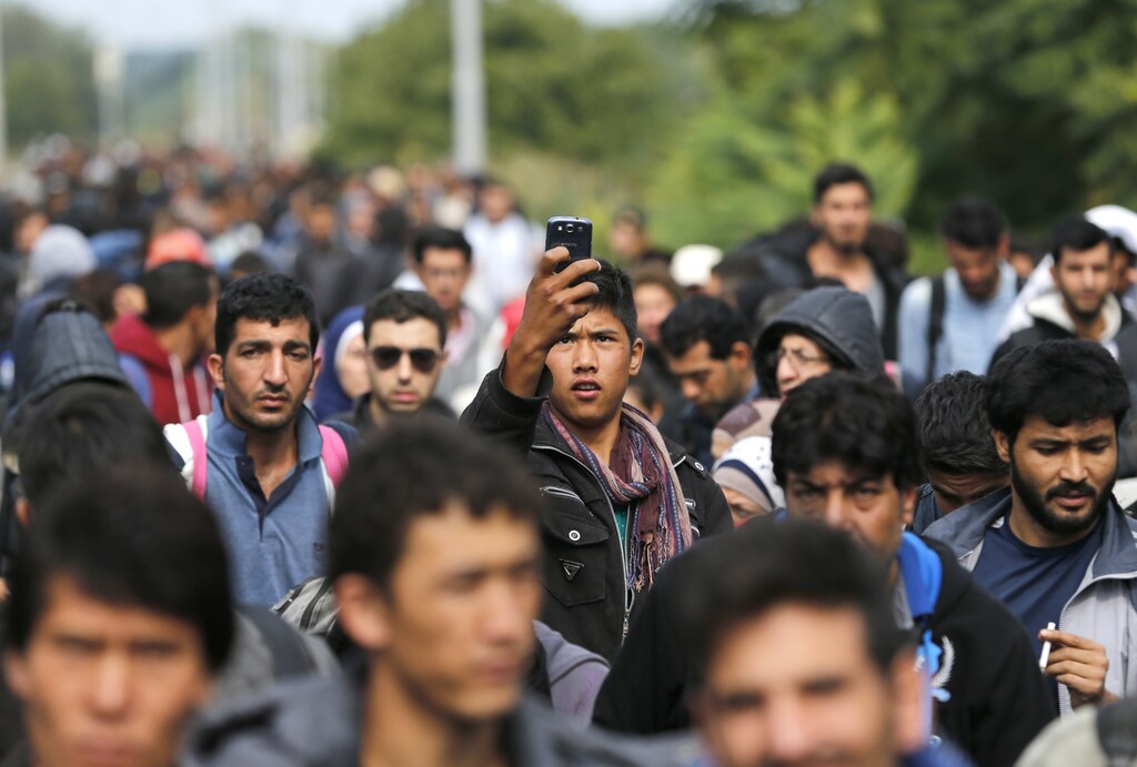 A migrant takes a picture with a mobile phone as he and others walk towards the Hungarian border after arriving at the train station in Botovo, Croatia September 24, 2015. Almost 50,000 migrants have flowed into European Union-member Croatia via Serbia in little over a week since Hungary, northern neighbour to both countries, barred their entry to the EU by sealing its border with Serbia with a metal fence. Croatia is sending the migrants north across its border with Hungary, which passes them on to Austria, but Zagreb says it cannot cope with the pace, leading to desperate and sometime angry scenes at over-crowded camps and railway stations. REUTERS/Antonio Bronic - LR2EB9O12LN4R