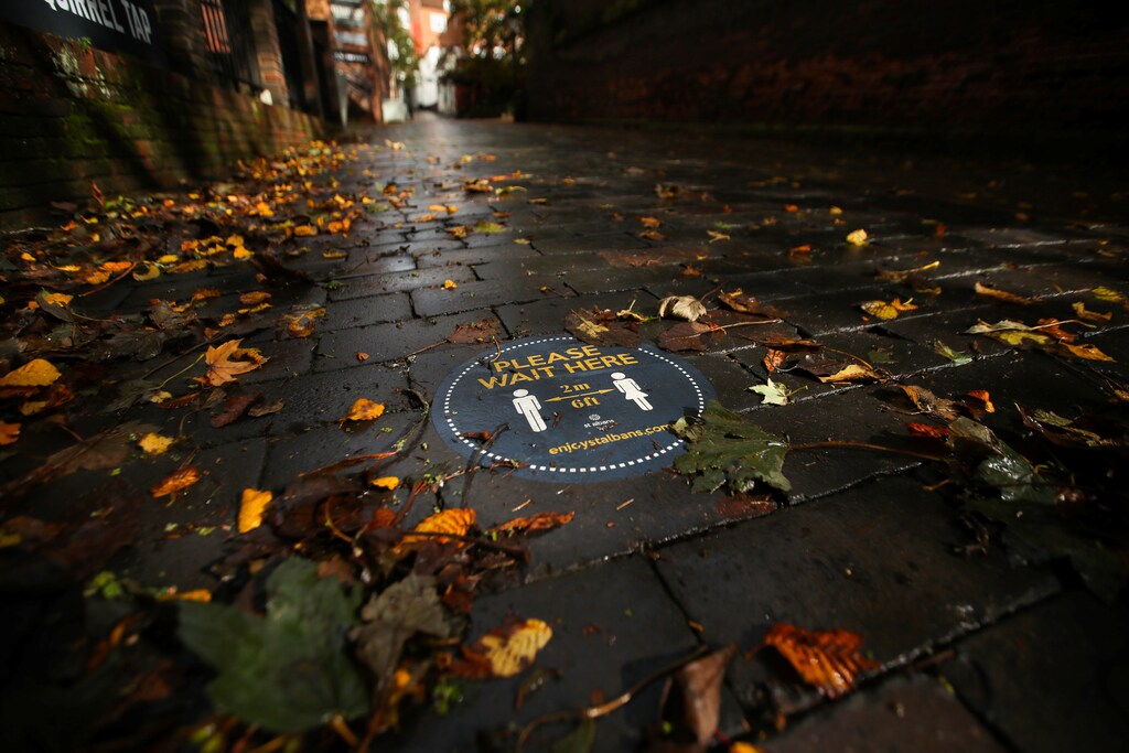 A social distancing sign is seen among autumn leaves, following the outbreak of the coronavirus disease (COVID-19), in St. Albans, Britain, October 8, 2020. REUTERS/Peter Cziborra - RC2CEJ9AKYI7
