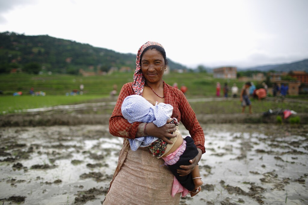 A Nepalese farmer breastfeeds her child before planting rice saplings in a rice paddy field during Asar Pandra festival in Bhaktapur June 29, 2013. Rice is considered the main staple for Nepalese and is planted during the Nepali month of Asar, which usually lies between June and July, typically seen by locals as an auspicious month for planting rice.