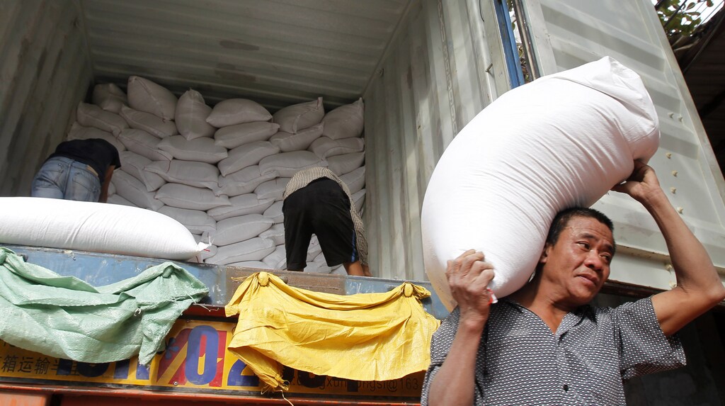 Workers unload bags of rice from a container to a store outside Hanoi November 26, 2013. Vietnam submitted the lowest price to supply 500,000 tonnes of rice to the Philippines, beating Thailand's offer for grain to boost stocks depleted by Typhoon Haiyan, Manila's grain procurement agency said on Tuesday. Vietnam, the world's second-biggest rice exporter after India last year, offered to deliver the entire volume within three months at $462.25 per tonne, with a first shipment of at least 120,000 tonnes by Dec. 31. REUTERS/Kham (VIETNAM - Tags: BUSINESS FOOD AGRICULTURE) - GM1E9BQ1L6V01