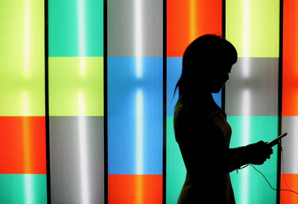 A booth assistant checks out a video game of BTD STUDIO Co. Ltd. and Quattro Media Corporation with a mobile phone during Tokyo Game Show 2006 at Makuhari Messe in Chiba, east of Tokyo, September 22, 2006. The three-day show will feature exhibits by 148 companies. REUTERS/Kiyoshi Ota