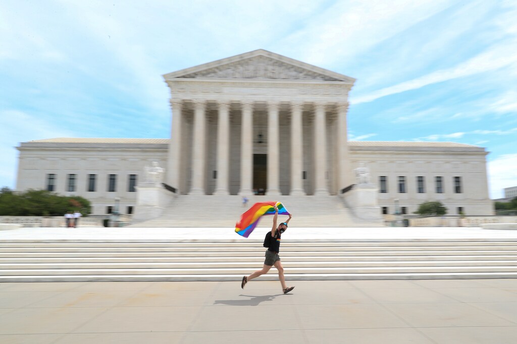 Joseph Fons holding a Pride Flag, runs in front of the U.S. Supreme Court building after the court ruled that a federal law banning workplace discrimination also covers sexual orientation, in Washington, D.C., U.S., June 15, 2020. REUTERS/Tom Brenner TPX IMAGES OF THE DAY - RC2S9H9RU8J1