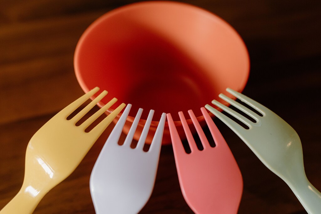 Colourful plastic forks on an orange bowl.