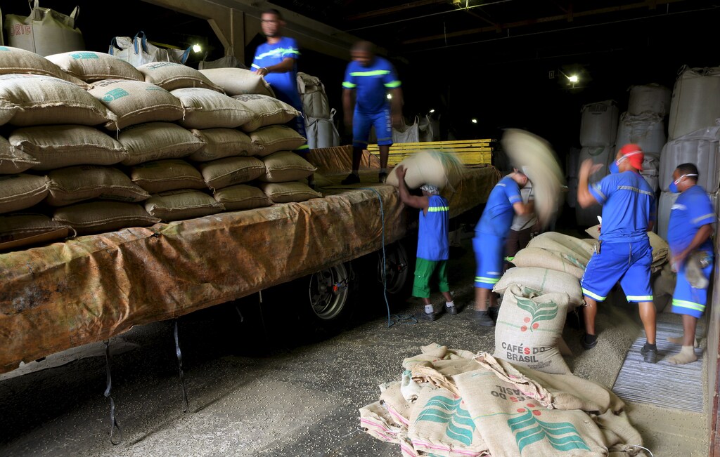 workers unload large canvass sacks filled with coffee beans