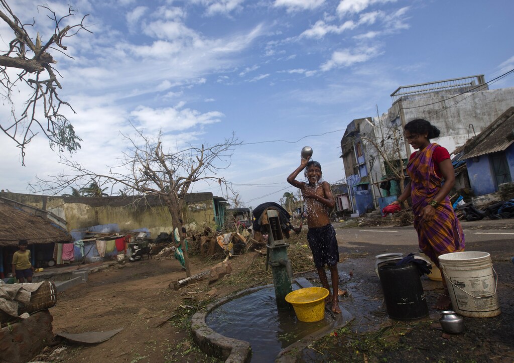 A boy bathes at a public hand pump after Cyclone Phailin hit Gopalpur in Ganjam district in the eastern Indian state of Odisha October 13, 2013. India's strongest storm in 14 years left a trail of destruction along the country's east coast on Sunday, but little loss of life was reported after close to a million people took refuge in shelters. Cyclone Phailin was expected to dissipate within 36 hours, losing momentum as it headed inland after making landfall on Saturday from the Bay of Bengal, bringing winds of more than 200 kph (125 mph) to rip up homes and tear down trees. REUTERS/Ahmad Masood (INDIA - Tags: ENVIRONMENT DISASTER) - GM1E9AE005Z01