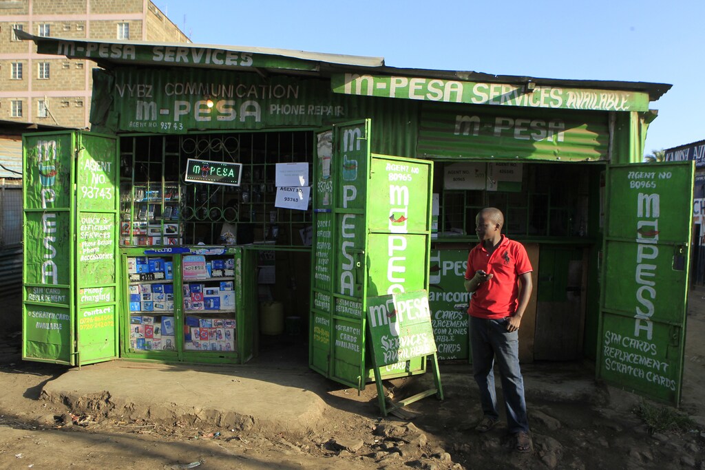 A man waits for M-Pesa customers at his shop in Kibera in Kenya's capital Nairobi December 31, 2014