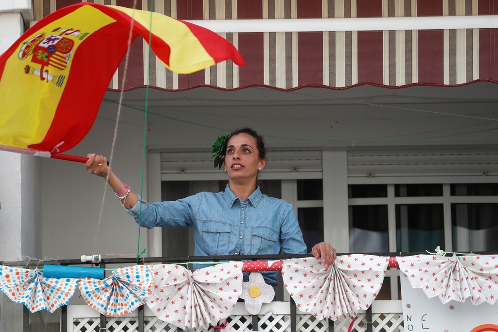 Una mujer agita una bandera española después de aplaudir en apoyo de los trabajadores de la salud, durante el encierro en medio del brote de la enfermedad coronavirus (COVID-19), en Ronda, al sur de España, el 18 de abril de 2020.