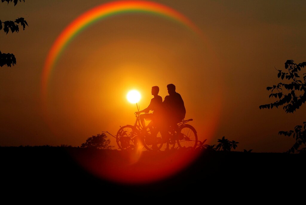 Boys are silhouetted against the setting sun as they ride bicycles on the outskirts of Agartala, India, November 21, 2016