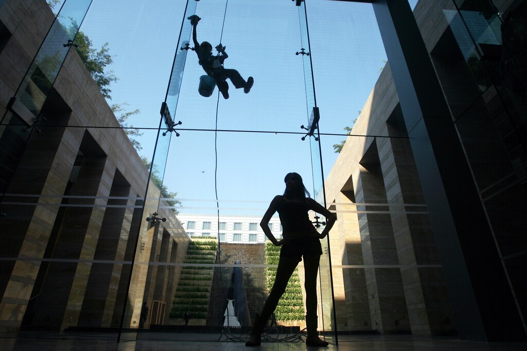A model poses for photographers during auditions for an upcoming fashion week as a worker cleans a window at a hotel in Mumbai February 2, 2009. Models from India and other countries participated in the auditions for the Lakme Fashion Week which will be held in March. REUTERS/Arko Datta (INDIA) - GM1E5221UDY01