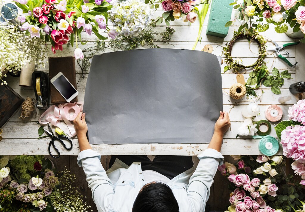 Florist Showing Empty Design Space Paper on Wooden Table with Fresh Flowers Decorate