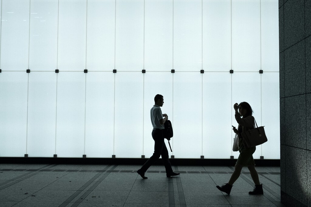 Two officer workers are seen walking past a lit-up office.