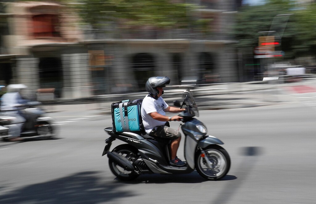 A scooter rider wearing a Deliveroo backpack drives in the central Barcelona, Spain, July 23, 2019.
