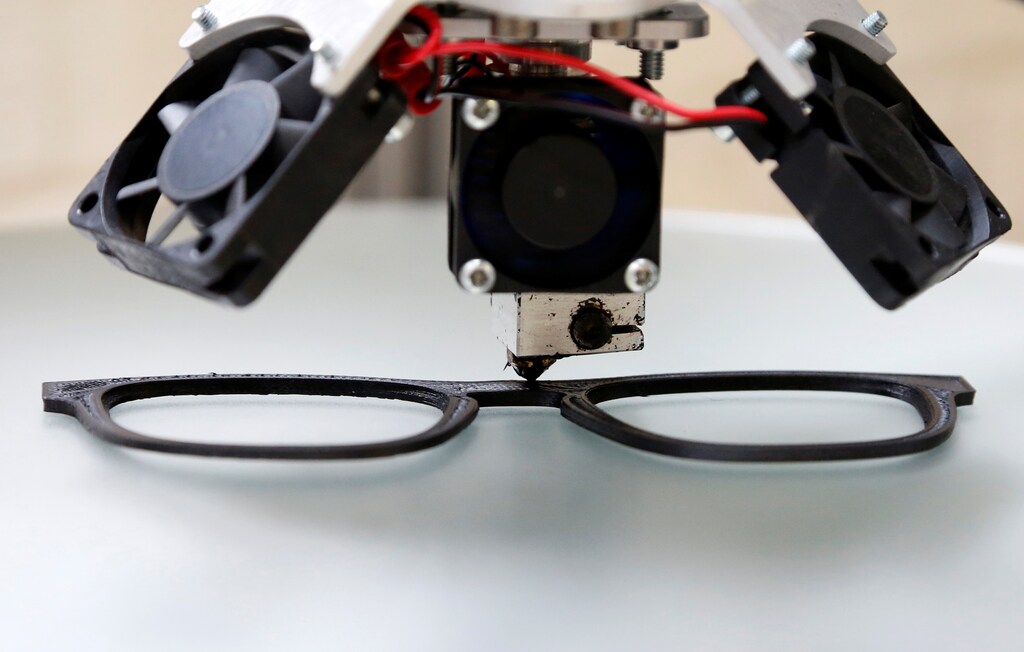 A 3D printing machine applies recycled plastic to shape sunglasses at Belgian start-up w.r.yuma in Antwerp, Belgium, August 30, 2017. Picture taken August 30, 2017. REUTERS/Francois Lenoir - RC1CB1DAAEC0