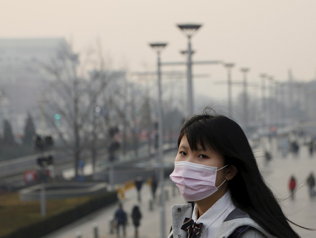 A school girl wearing a protective mask makes her way in a shopping district as China's capital Beijing braces for four days of choking smog starting Saturday, in Beijing, China, December 19, 2015. REUTERS/Kim Kyung-Hoon - GF10000271179
