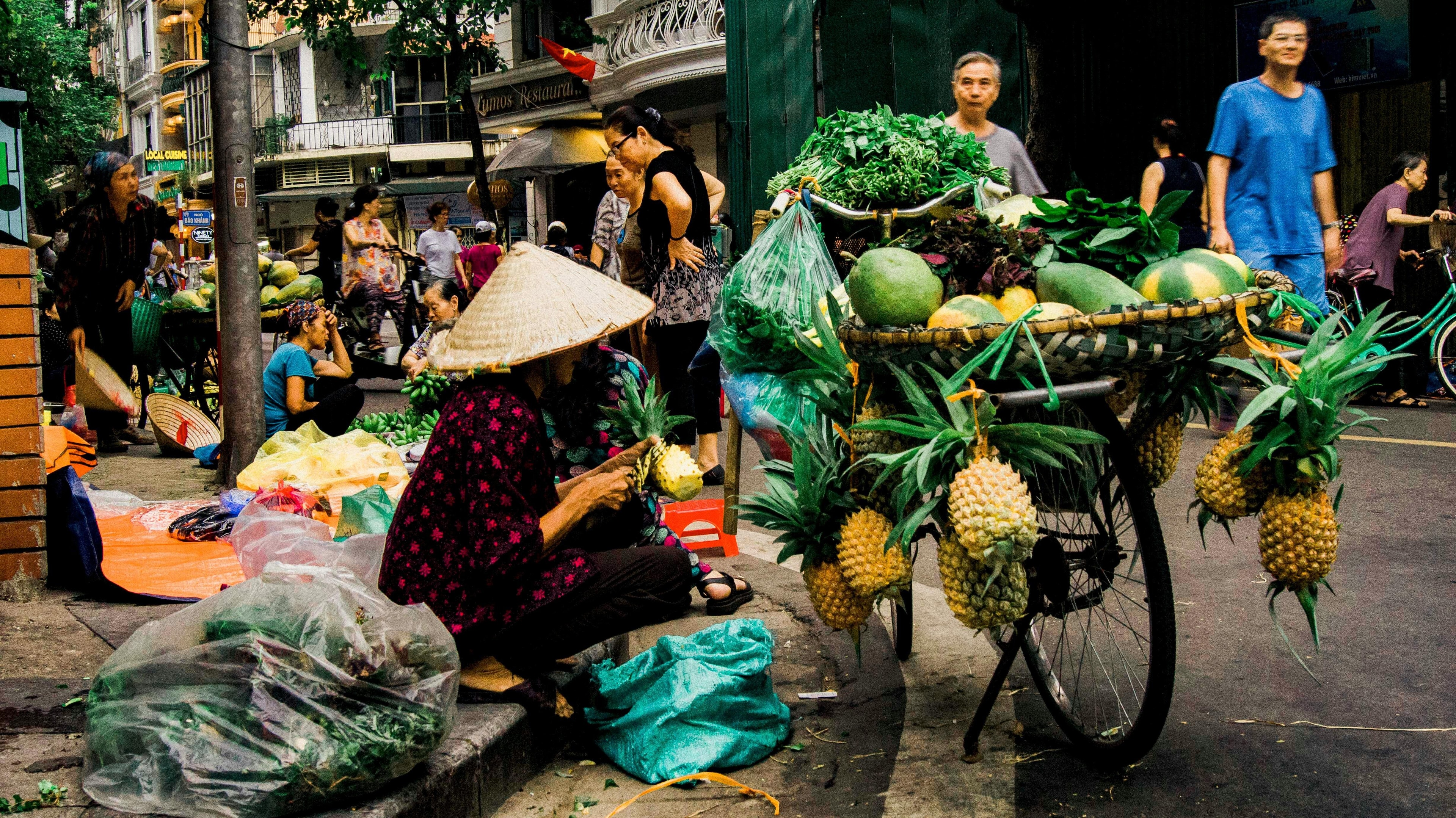 Woman in hat selling fruit on the street; alleviate poverty; entrepreneurship.