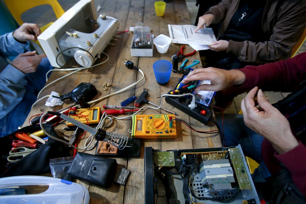 People work on non-functioning electrical items at a so-called 'Repair Cafe' in Berlin's Kreuzberg district September 30, 2013. One day a month volunteers meet-up and assist people in repairing their electronic items for free at the cafe in the German capital. REUTERS/Tobias Schwarz (GERMANY - Tags: SOCIETY) - BM2E99U1DHA01
