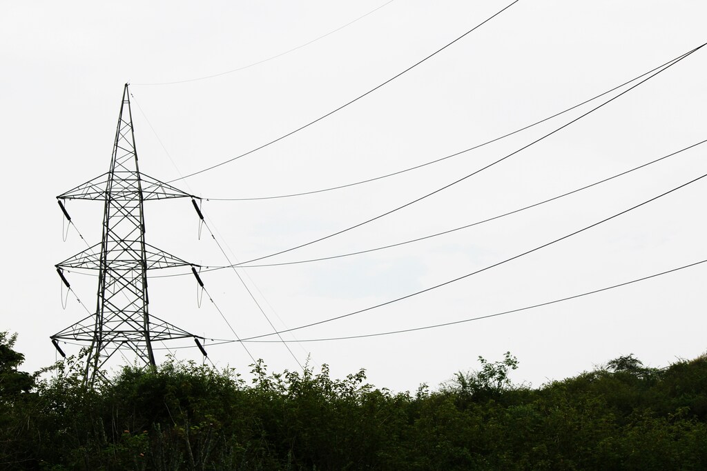 High-voltage transmission tower and power lines representing electric grid infrastructure.