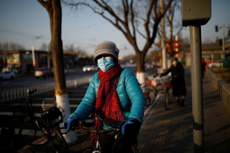A woman wearing a face mask rides a bicycle as the country is hit by an outbreak of the new coronavirus, in Beijing, China January 30, 2020. REUTERS/Carlos Garcia Rawlins - RC26QE9WR9RA