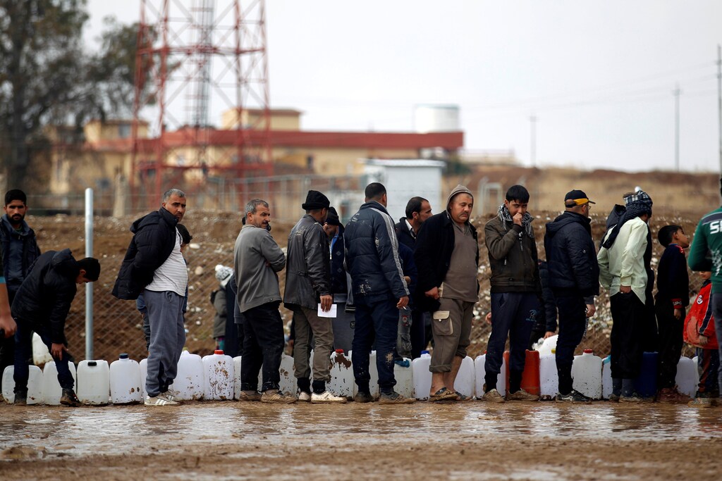 Displaced Iraqis, who fled the Islamic State stronghold of Mosul, carry empty containers as they wait in line to fill them with fuel to be used for cooking and lighting at Khazer camp, Iraq December 26, 2016. REUTERS/Khalid al Mousily - RTX2WIMU