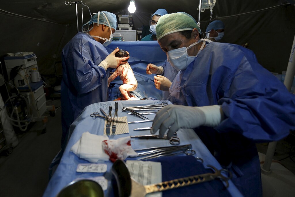 Moroccan doctors carry a Syrian baby Siwar, who was born by caesarean section in a field hospital in Al Zaatari refugee camp in the Jordanian city of Mafraq, near the border with Syria, March 7, 2016. Siwar is the third child of a Syrian family from Daraa who fled to Jordan two years ago. She is their second child to be born in the camp. Since the beginning of the Syrian crisis, 50-80 Syrian children were born in the Zaatari refugee camp each week, according to the official website of UNHCR. REUTERS/ Muhammad Hamed SEARCH "HAMED BORN" FOR THIS STORY. SEARCH "THE WIDER IMAGE" FOR ALL STORIES - GF10000340758
