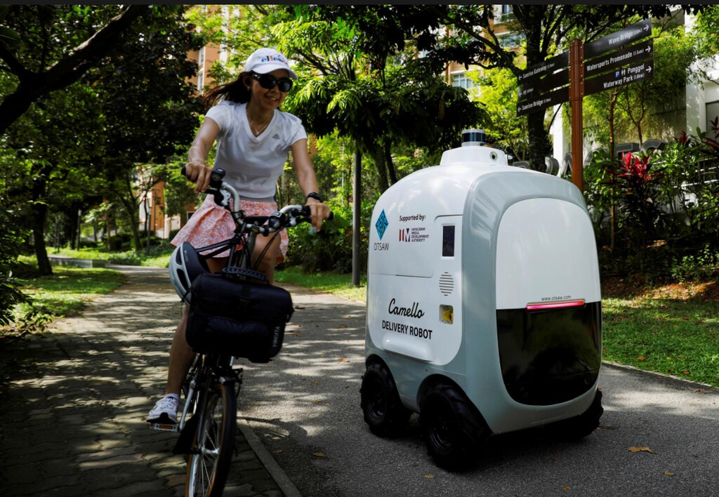 A cyclist passes as Camello, an autonomous grocery delivery robot, makes its way during delivery in Singapore.
