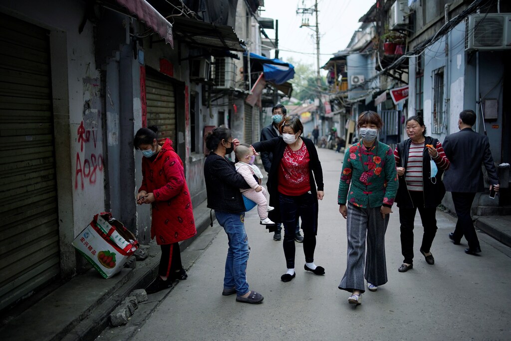 Residentes con máscaras faciales caminan en una antigua comunidad residencial bloqueada por barreras en Wuhan, provincia de Hubei, el epicentro del brote de la enfermedad coronavirus de China (COVID-19), el 5 de abril de 2020.