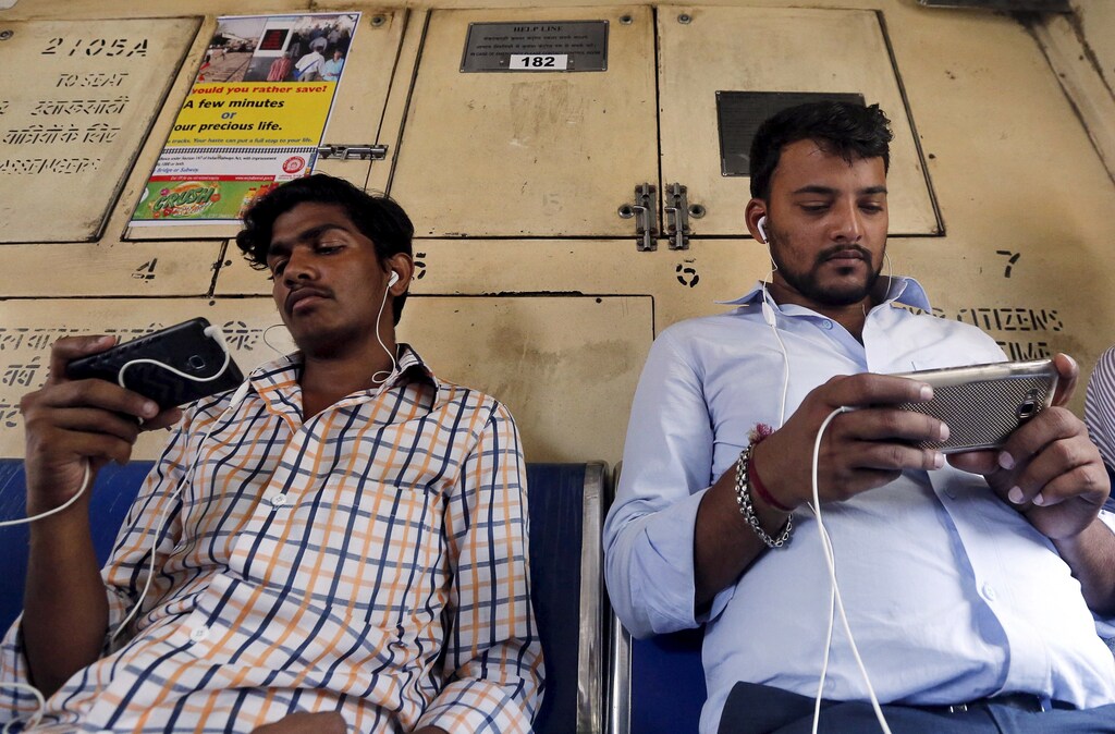 Commuters watch videos on their mobile phones as they travel in a suburban train in Mumbai, India, April 2, 2016. With smartphone sales booming and India preparing for nationwide 4G Internet access, India's film and TV industry hopes the ease of tapping your phone for the latest release will generate profits at last, overcoming the problems of woefully few cinemas and rampant piracy. Picture taken April 2, 2016. REUTERS/Shailesh Andrade - GF10000368981