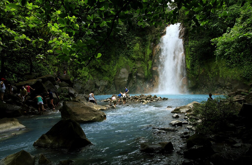 People swim in the Celeste river waterfall at Tenorio Volcano National Park in Upala March 18, 2008. The blue color of the lagoon, formed from chemical reactions of calcium carbonate and sulfur, is surrounded by amazing rainforest of 12,819 hectares of this park. The Celeste river carries its color for a distance of 36 km (22 miles). REUTERS/Juan Carlos Ulate (COSTA RICA) - GM1E43J0V1A01