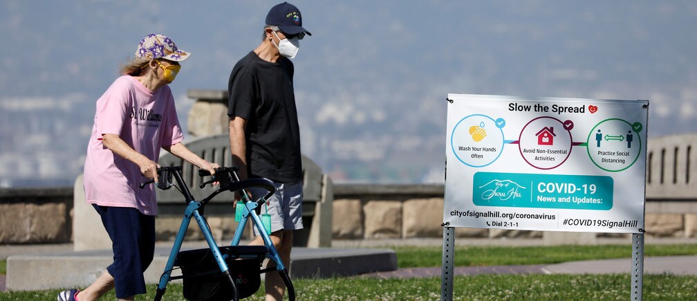 Una pareja de ancianos usan máscaras cuando hacen ejercicio en un parque.