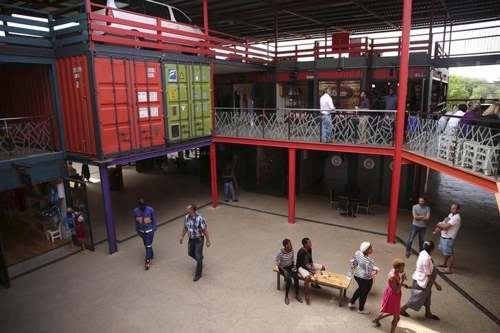 Workers and customers walk at 27 Boxes, a mosaic-coloured retail centre built entirely of old shipping containers, in Melville, south west of Johannesburg, South Africa October 2, 2015. A short drive west of Johannesburg on the edge of a fading bohemian high street stands 27 Boxes. Opened in August, it consists of twenty-seven iron containers stacked Lego-like into three floors of stores ranging from a green grocer, al fresco coffee houses and a Philadelphia-style grill house, to a toddler-wear boutique and bicycle rental shop. Picture taken October 2, 2015. REUTERS/Siphiwe Sibeko