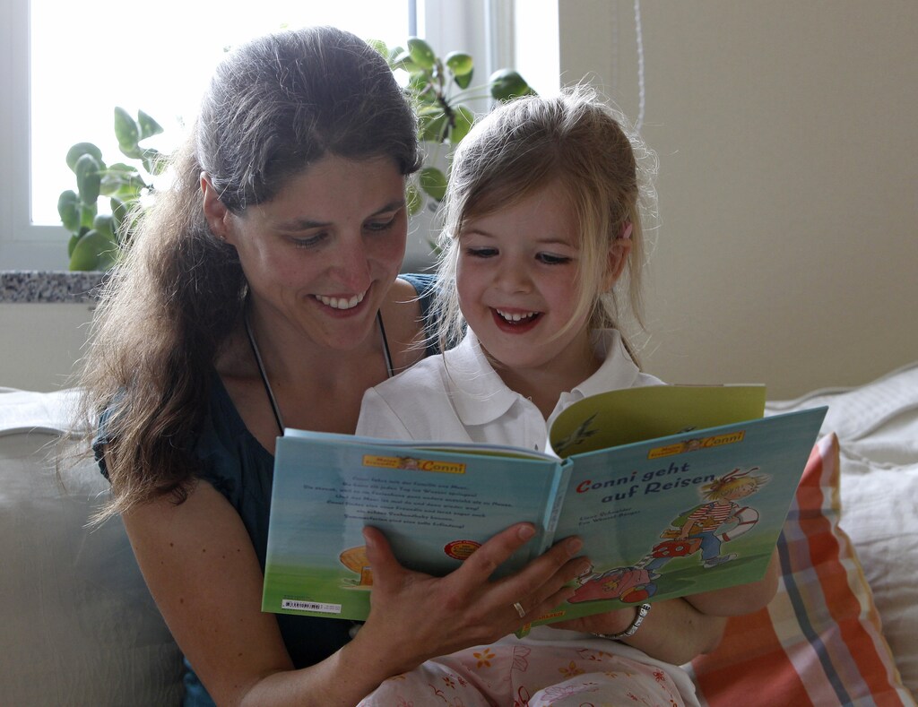 Claudia reads a book with daughter Katharina at home in Durach, southern Germany June 20, 2012. German Chancellor Angela Merkel is looking to establish a childcare allowance for stay-at-home mothers. The draft law, known as Betreuungsgeld, will provide mothers who stay at home with their children, about 150 Euros ($190) per month. REUTERS/Michaela Rehle (GERMANY - Tags: EDUCATION POLITICS SOCIETY) - RTR33XDW