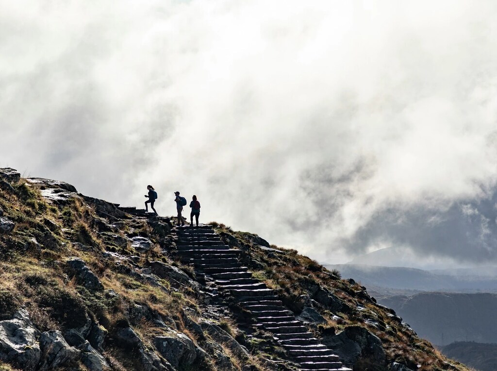 Tres personas suben las escalinatas de una montaña. Durante las turbulencias geopolíticas, las potencias intermedias determinarán si el mundo supera sus desafíos.