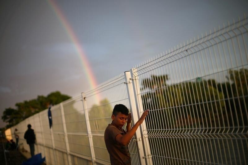 A Central American migrant, part of a caravan trying to reach the U.S, is pictured as he waits to open the gate on the bridge that connects Mexico and Guatemala in Ciudad Hidalgo, Mexico, October 21, 2018.