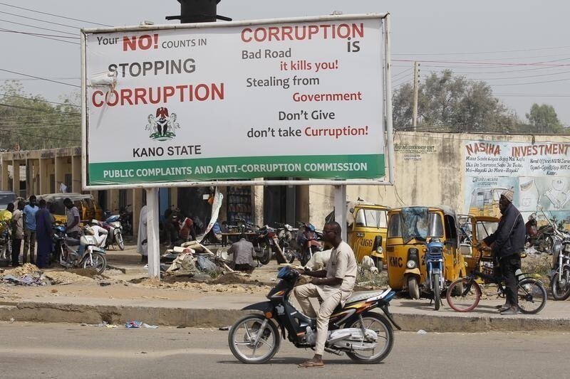 A man on a motorcycle sits near a signboard campaigning against corruption along a road in Dangi district in Nigeria's northern city of Kano, January 19, 2016. True to his election promises, Nigerian President Muhammadu Buhari has gone all out on corruption, alleging mind-boggling sums plundered from state coffers and giving investigators licence to pull in big hitters once thought untouchable. Now comes the hard part: making the charges stick. The first test comes on Wednesday with the opening of the trial of former National Security Advisor Sambo Dasuki, accused of fraud over $68 million of defence spending, part of a wider $2.1 billion in arms deals under scrutiny