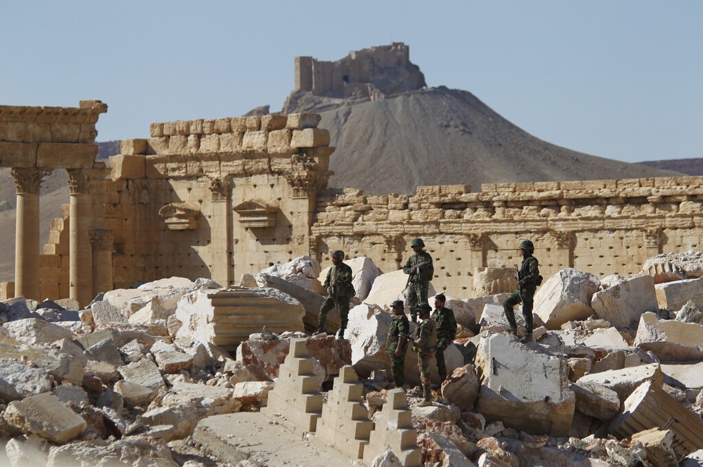 Syrian army soldiers stands on the ruins of the Temple of Bel in the historic city of Palmyra, in Homs Governorate, Syria April 1, 2016. The Fakhreddin's Castle is seen in the background. REUTERS/Omar Sanadiki TPX IMAGES OF THE DAY SEARCH "PALMYRA SANADIKI" FOR THIS STORY. SEARCH "THE WIDER IMAGE" FOR ALL STORIES - RTSD6NS