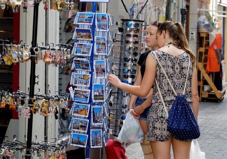 Tourists look at postcards at a souvenir shop in the Old Town of Valencia, Spain August 17, 2017. REUTERS/Heino Kalis