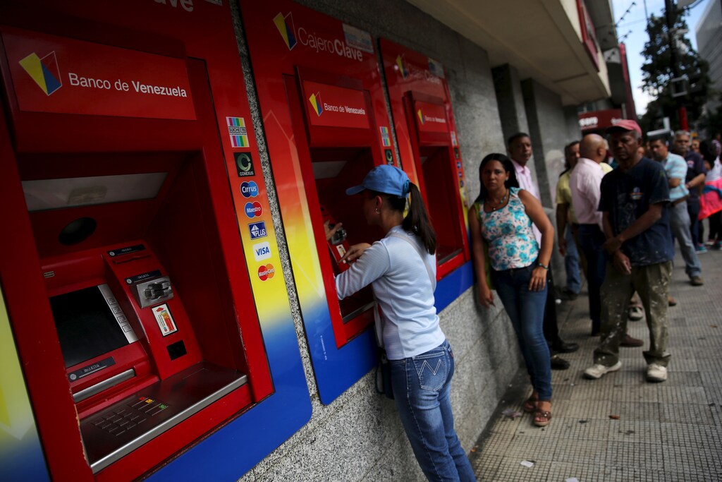 Venezuelans line up to withdraw cash from an automated teller machine (ATM) outside a Venezuela branch in Caracas December 4, 2015. Polarized Venezuela heads to the polls this weekend with a punishing recession forecast to rock the ruling Socialists and propel an optimistic opposition to its first legislative majority in 16 years. REUTERS/Nacho Doce - GF10000254959