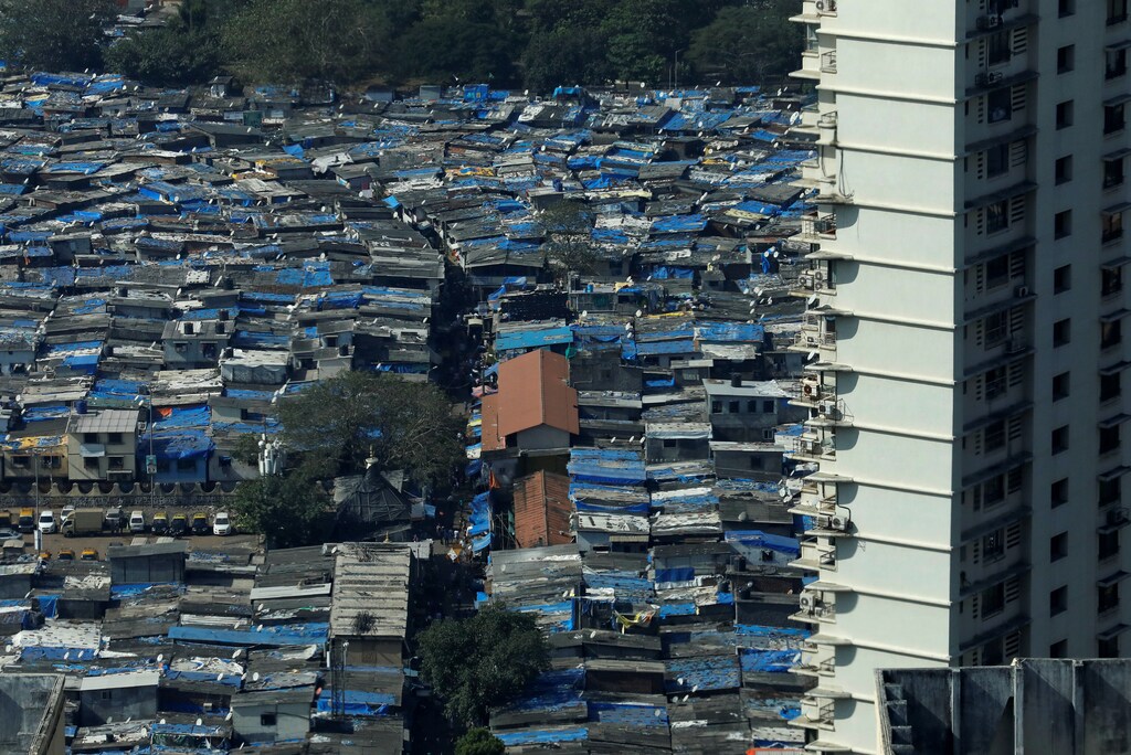 A high rise residential building is seen next to a slum in Mumbai, India