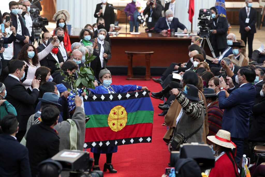 Constitutional assembly president Elisa Loncon holds up a flag as assembly members gather for the first session to draft a new constitution, in Santiago