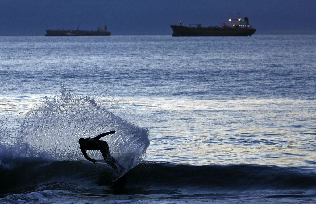 A surfer rides a wave during sunset in Vina del Mar city, about 75 miles (121 Km) northwest of Santiago, March 20, 2010. People slowly return the normal life in the coastal border after suffering an earthquake and tsunamis in much of southern Chile on February 27, 2010. REUTERS/Eliseo Fernandez (CHILE - Tags: SOCIETY IMAGES OF THE DAY) - GM1E63L0NRZ01