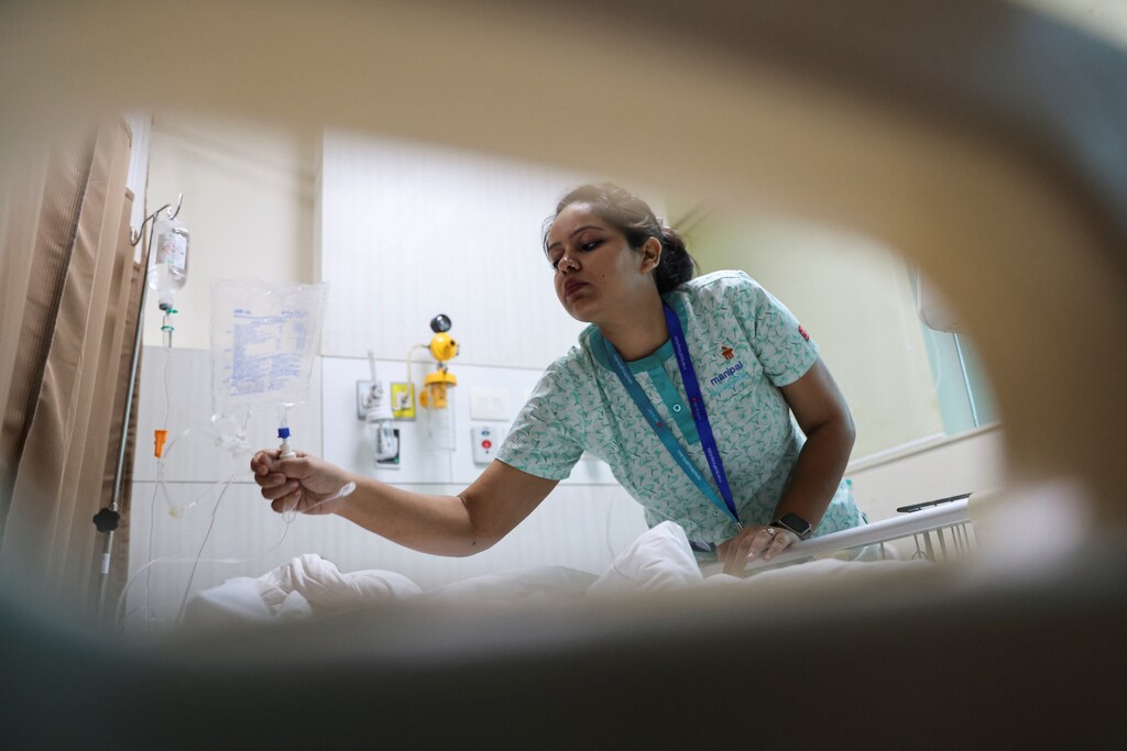 A healthcare worker helps a patient at a hospital in New Delhi, India.