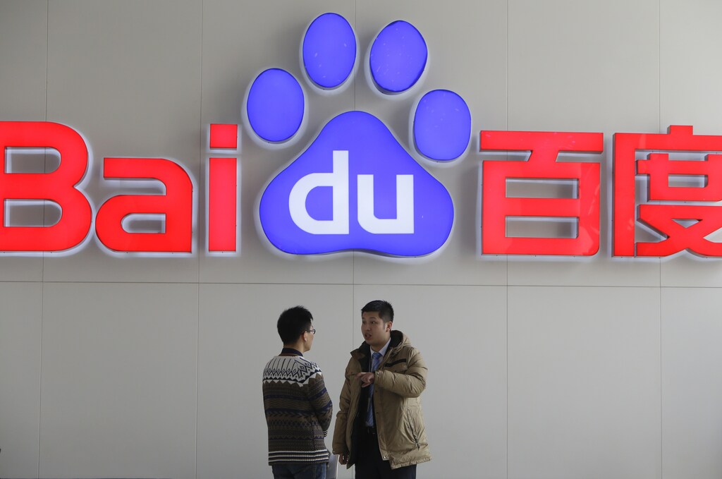 People talk in front of a Baidu's company logo at Baidu's headquarters in Beijing January 16, 2014. China's Baidu Inc knows where you are, where you're going and when you want dumplings, guiding you from web page to restaurant when you use its search engine.