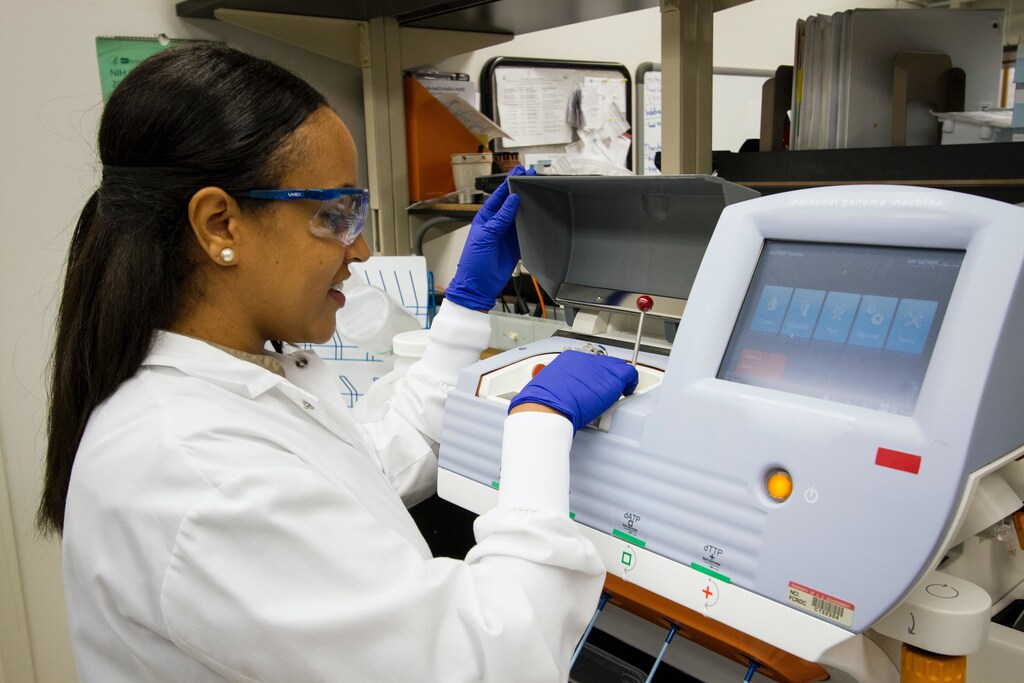 woman scientist loading DNA samples in machine in lab - genomic data genome global consortium data-sharing governance