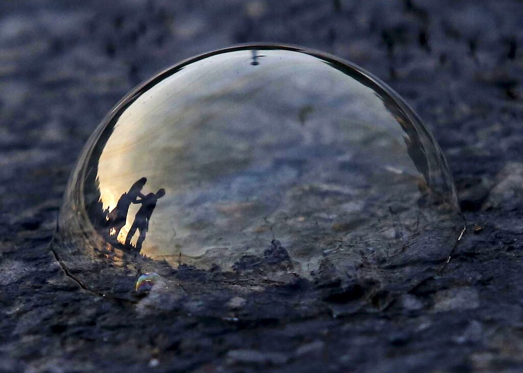 People are reflected on a soap bubble lying on a road during the evening in New Delhi, India, June 23, 2015. REUTERS/Anindito Mukherjee TPX IMAGES OF THE DAY - GF10000136753