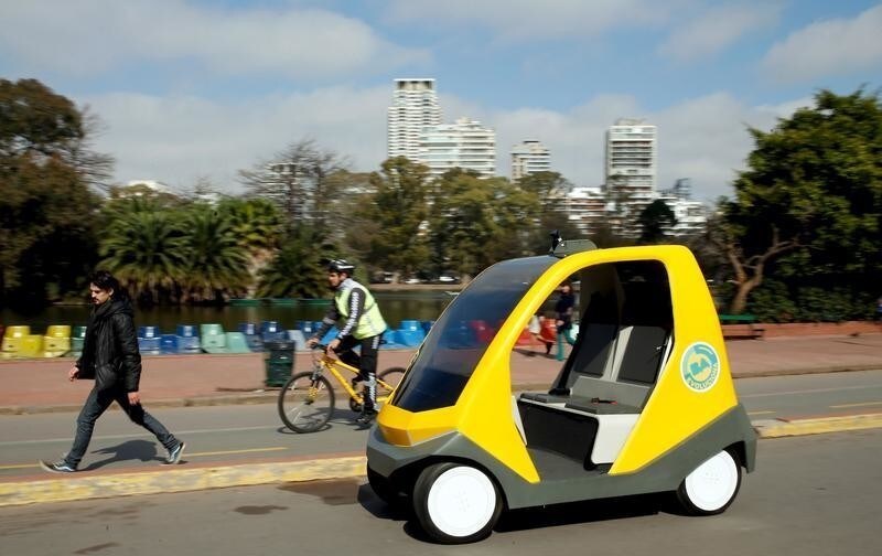 A man walks next to a prototype of an autonomous electric vehicle during its presentation in Buenos Aires, August 19, 2015. The autonomous vehicle, the first of its kind developed in Argentina, is able to fulfill the main functions of mobility of a traditional car but autonomously through the use of artificial intelligence that enables it to detect their surroundings and move without human intervention.